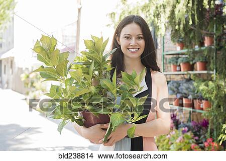 Picture - Thai woman shopping for potted plant in city. Fotosearch