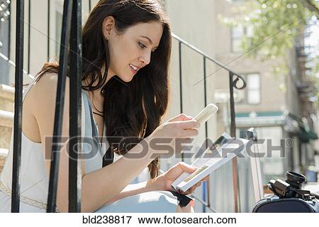 Thai woman sitting on urban staircase with cell phone and guidebook View Large Photo Image Stock Photo - Thai woman sitting on urban staircase with cell phone and guidebook. Fotosearch