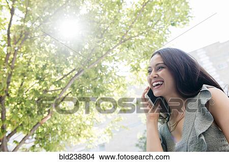 Thai woman talking on cell phone under tree View Large Photo Image Picture - Thai woman talking on cell phone under tree. Fotosearch