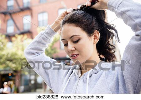 Stock Photography - Thai woman tying hair in ponytail. Fotosearch