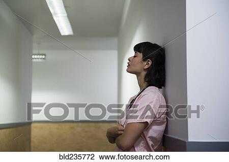 Tired Hispanic nurse leaning on wall in hospital corridor View Large Photo Image Stock Image - Tired Hispanic nurse leaning on wall in hospital corridor. Fotosearch