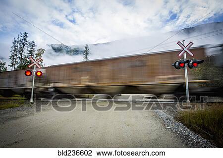 Stock Image - Train speeding through railroad crossing. Fotosearch