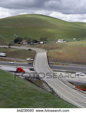 Stock Image - Trucks and cars driving under freeway overpass. Fotosearch