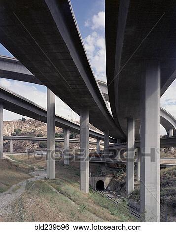 Trucks and cars driving under freeway overpass View Large Photo Image Stock Photograph - Trucks and cars driving under freeway overpass. Fotosearch