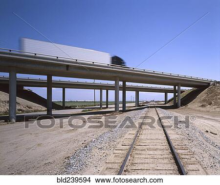 Trucks driving on freeway overpass over train track View Large Photo Image Picture - Trucks driving on freeway overpass over train track. Fotosearch