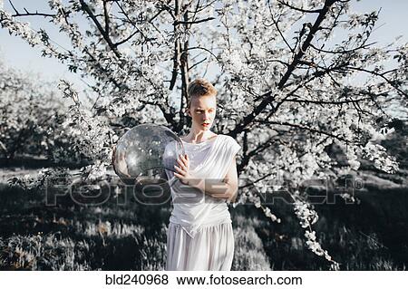 Unusual Caucasian teenage girl holding glass helmet near tree View Large Photo Image Stock Photo - Unusual Caucasian teenage girl holding glass helmet near tree. Fotosearch