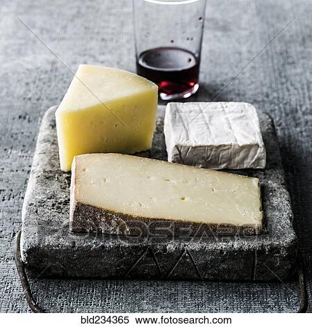 Stock Photography - Variety of wedges of cheese on cutting board with red wine. Fotosearch