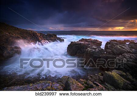 Stock Photo - Waves flowing on rocky beach. Fotosearch