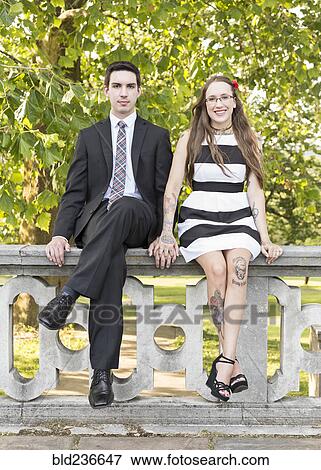 Well-dressed Caucasian couple sitting on wall at park View Large Photo Image Stock Photo - Well-dressed Caucasian couple sitting on wall at park. Fotosearch