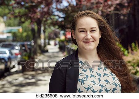 Stock Photo - Wind blowing hair of Caucasian woman on city sidewalk. Fotosearch