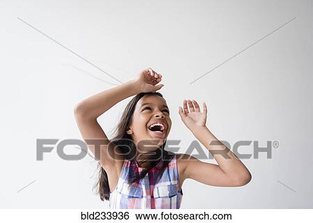 Stock Photograph - Wind blowing hair of smiling Mixed Race girl . Fotosearch