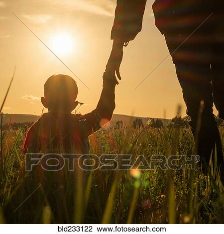 Woman and son holding hands in field at sunset View Large Photo Image Stock Image - Woman and son holding hands in field at sunset. Fotosearch
