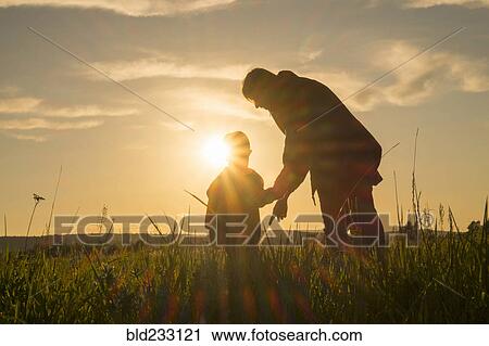 Woman and son standing in field at sunset View Large Photo Image Stock Image - Woman and son standing in field at sunset. Fotosearch