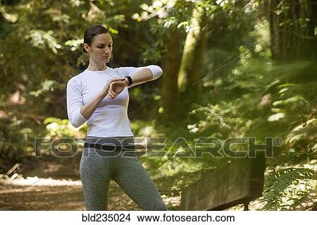 Woman checking wristwatch on forest path View Large Photo Image Picture - Woman checking wristwatch on forest path. Fotosearch