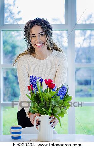 Woman holding vase with flowers View Large Photo Image Picture - Woman holding vase with flowers. Fotosearch