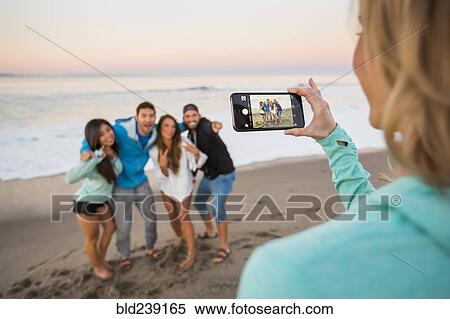 Woman photographing friends at beach with cell phone View Large Photo Image Stock Photography - Woman photographing friends at beach with cell phone. Fotosearch
