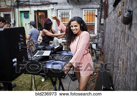 Stock Image - Woman playing music at party in backyard. Fotosearch