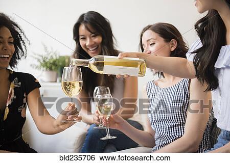 Woman pouring bottle of white wine for friends View Large Photo Image Stock Photograph - Woman pouring bottle of white wine for friends. Fotosearch