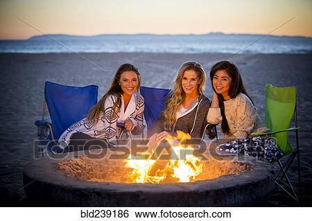 Woman relaxing on beach at fire pit View Large Photo Image Stock Photograph - Woman relaxing on beach at fire pit. Fotosearch
