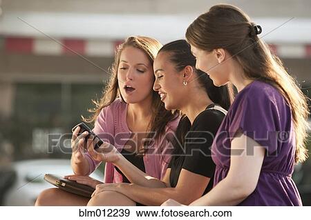 Stock Photo - Woman showing cell phone to friends. Fotosearch