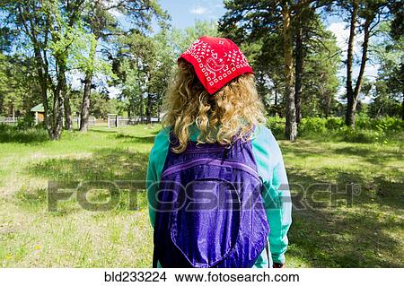 Picture - Woman wearing bandana carrying backpack in park. Fotosearch