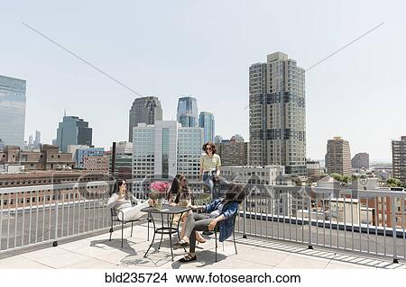 Picture - Women drinking wine on urban rooftop. Fotosearch