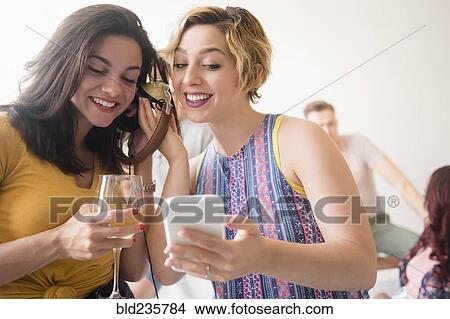 Picture - Women listening to cell phone with headphones. Fotosearch