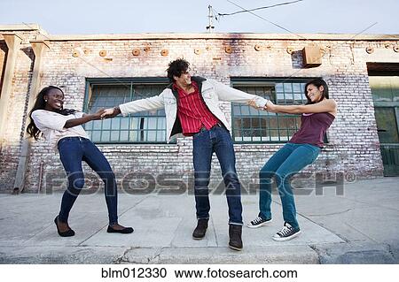 Women pulling on male friend's arms View Large Photo Image Stock Image - Women pulling on male friend's arms. Fotosearch