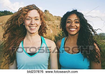 Stock Photograph - Women standing near boulder in wind. Fotosearch