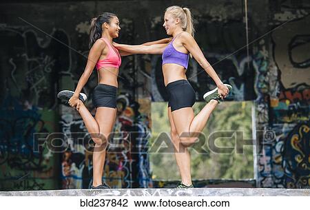 Stock Image - Women stretching legs near graffiti. Fotosearch