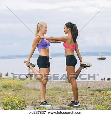 Stock Photo - Women stretching legs near lake. Fotosearch