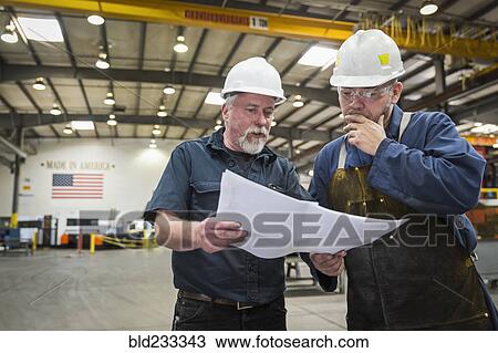 Workers examining paperwork in factory View Large Photo Image Stock Image - Workers examining paperwork in factory. Fotosearch