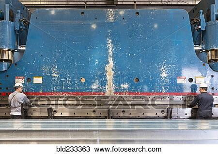 Stock Image - Workers fabricating metal in factory. Fotosearch