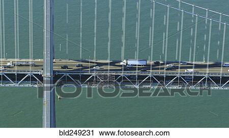 Stock Image - Aerial view of cars and trucks driving on bridge. Fotosearch