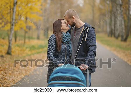 Stock Image - Affectionate Middle Eastern couple with stroller in park. Fotosearch