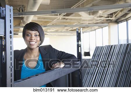 Stock Image - African American businesswoman standing in empty office. Fotosearch