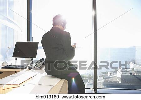 Stock Photo - African American businesswoman using cell phone in office. Fotosearch