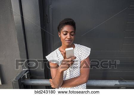 African American leaning on railing texting on cell phone View Large Photo Image Stock Image - African American leaning on railing texting on cell phone. Fotosearch