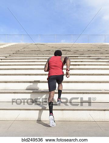 Stock Photograph - African American man running on bleachers. Fotosearch