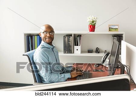 Picture - African American man using computer in office. Fotosearch