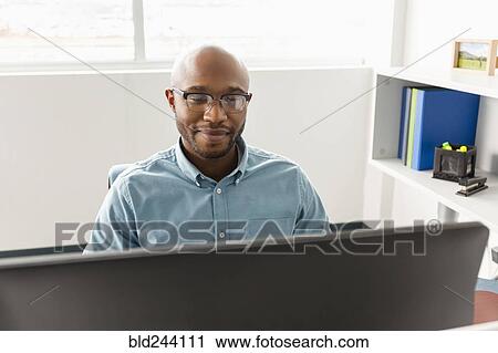 Stock Image - African American man using computer in office. Fotosearch