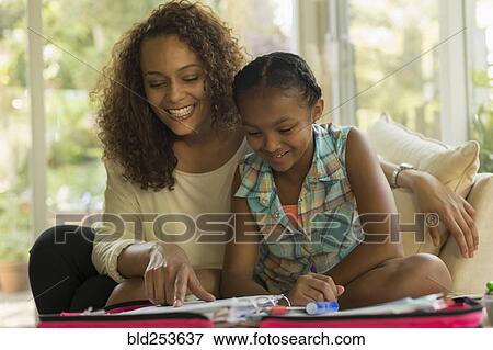 Stock Photo - African American mother helping daughter with homework. Fotosearch