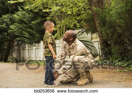 Stock Photograph - African American soldier tying shoelace for son. Fotosearch