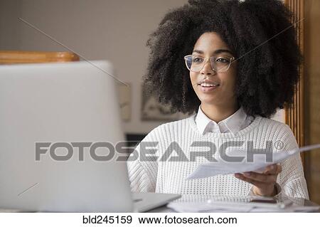 African American woman holding paperwork using laptop View Large Photo Image Stock Photo - African American woman holding paperwork using laptop. Fotosearch