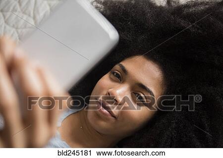 African American woman laying in bed texting on cell phone View Large Photo Image Stock Image - African American woman laying in bed texting on cell phone. Fotosearch