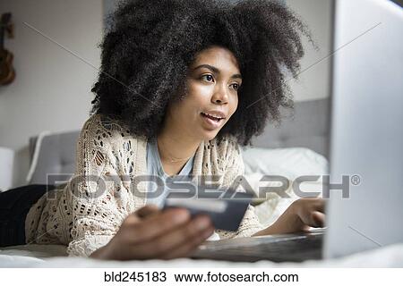 African American woman laying in bed online shopping with laptop View Large Photo Image Stock Image - African American woman laying in bed online shopping with laptop. Fotosearch