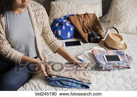 African American woman sitting on bed folding clothing View Large Photo Image Stock Image - African American woman sitting on bed folding clothing. Fotosearch