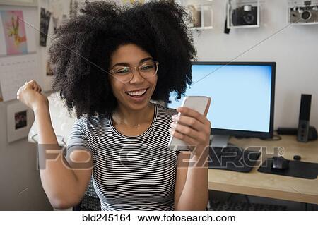 African American woman texting on cell phone and celebrating View Large Photo Image Picture - African American woman texting on cell phone and celebrating. Fotosearch