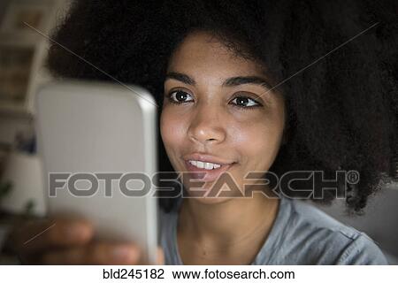 Stock Image - African American woman texting on cell phone. Fotosearch