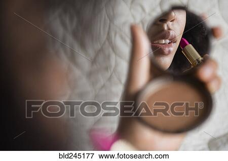 African American woman using compact applying lipstick View Large Photo Image Stock Photo - African American woman using compact applying lipstick. Fotosearch